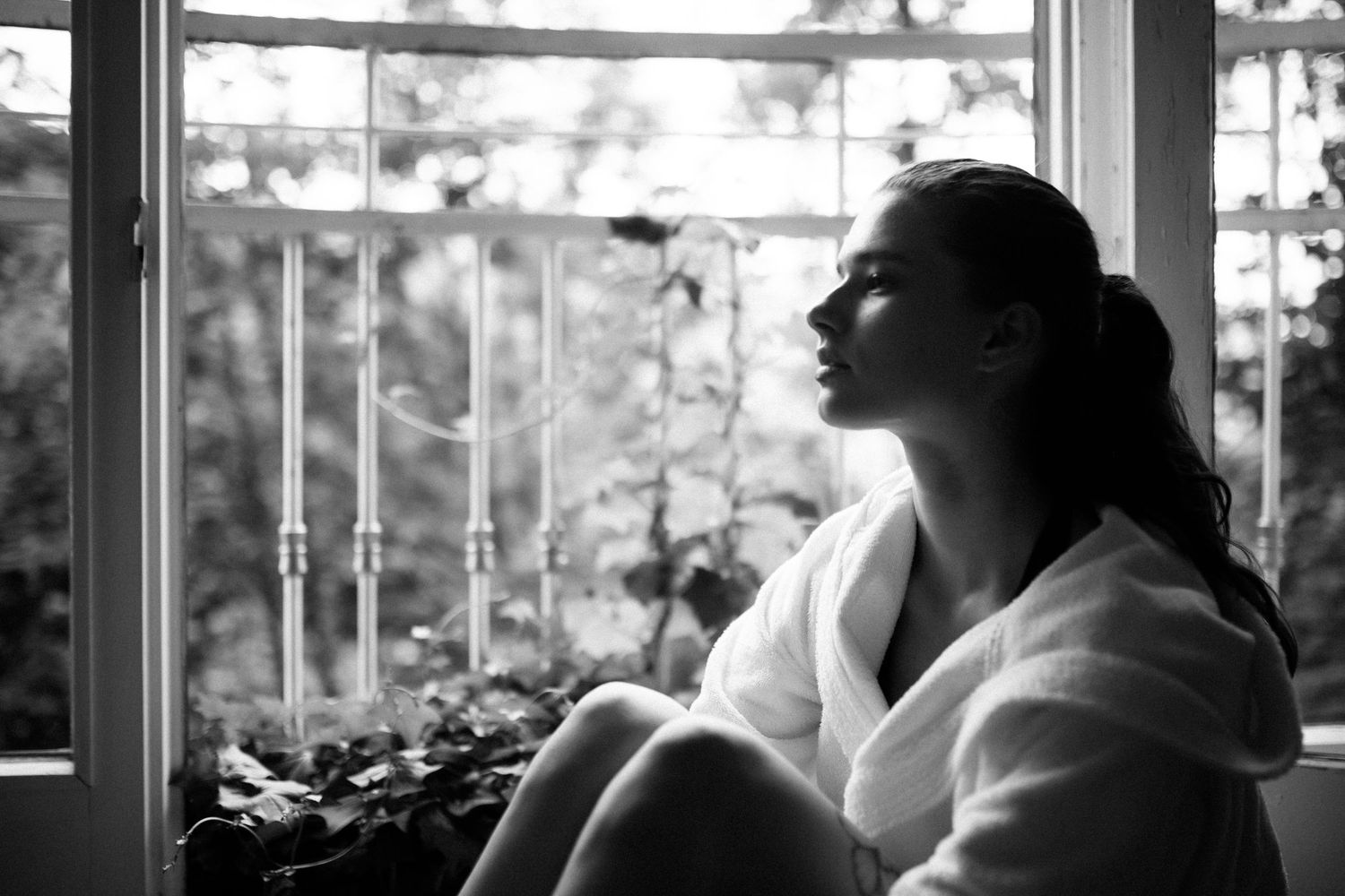 Peaceful contemplative moment by window in black and white photography.