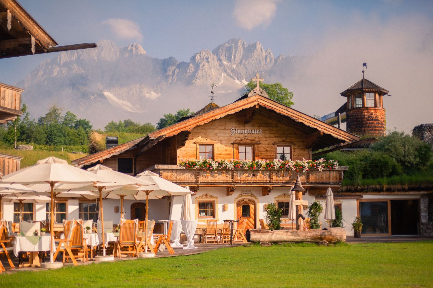 Traditional Alpine restaurant with mountain backdrop and outdoor seating area.