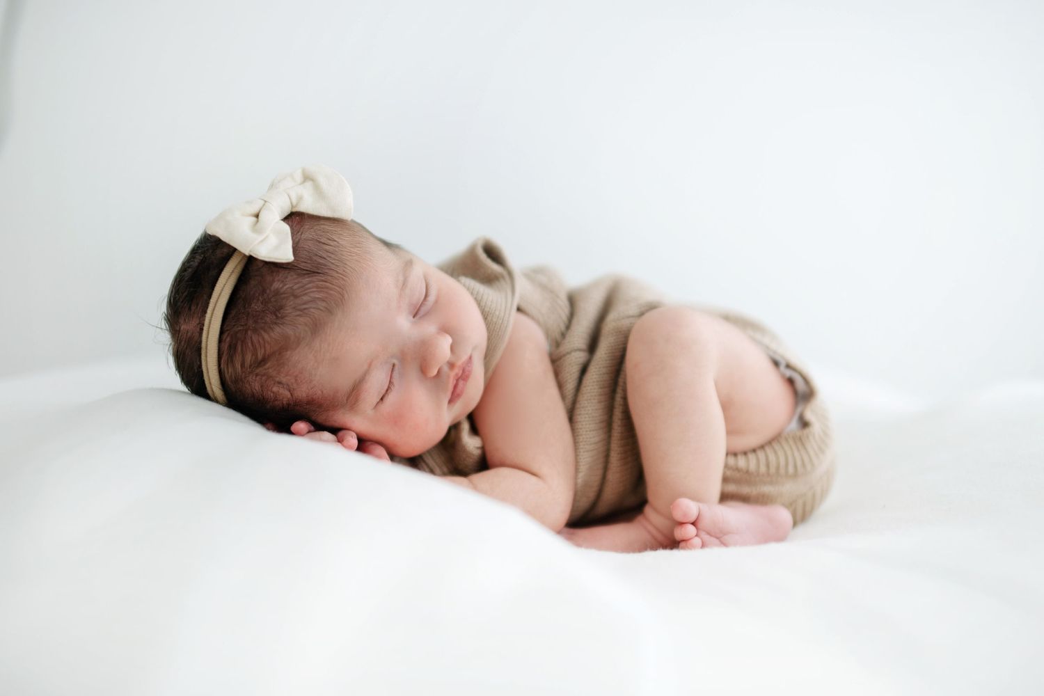 A newborn sleeps peacefully while parents look on lovingly.
