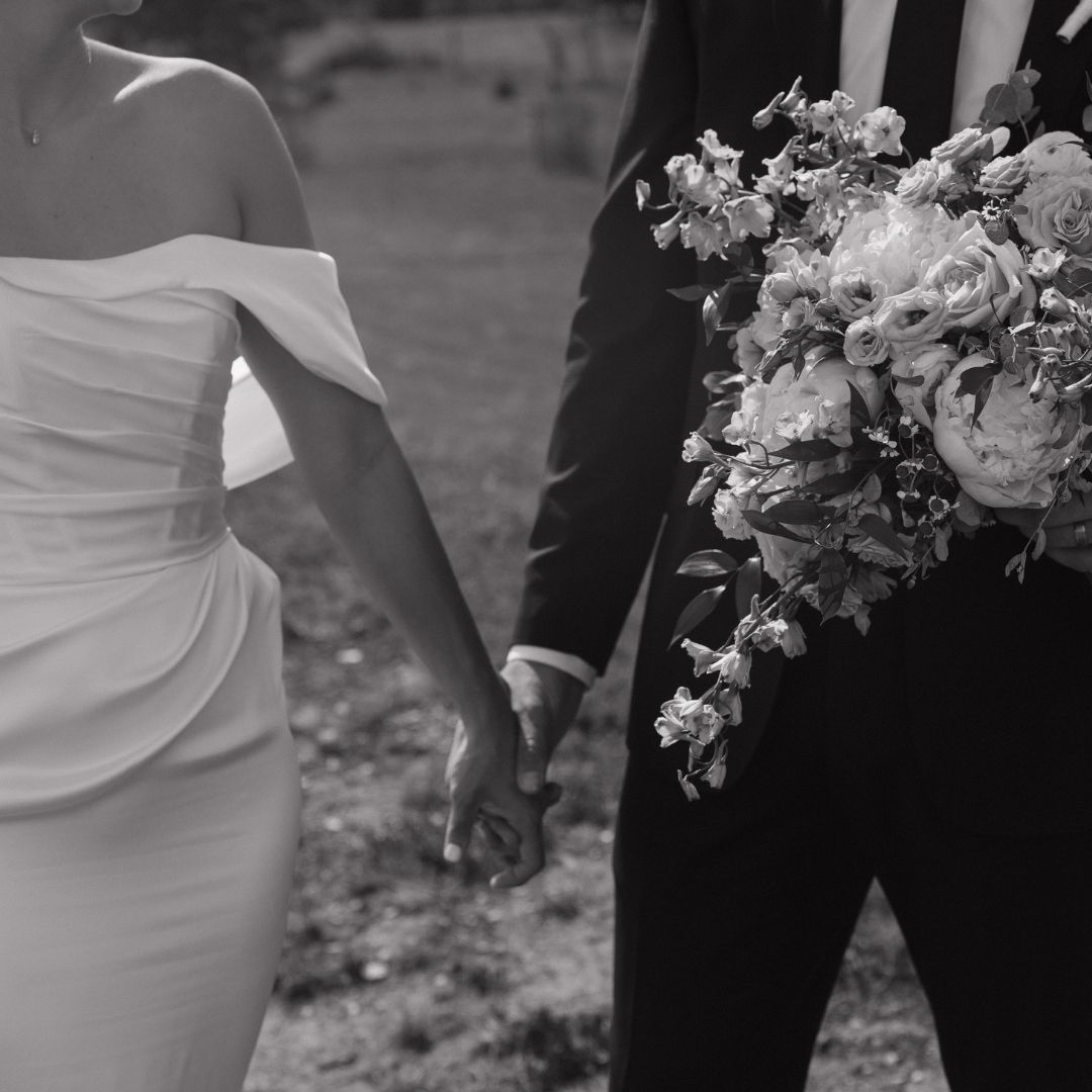 Formal wedding couple poses in black and white with elegant attire.