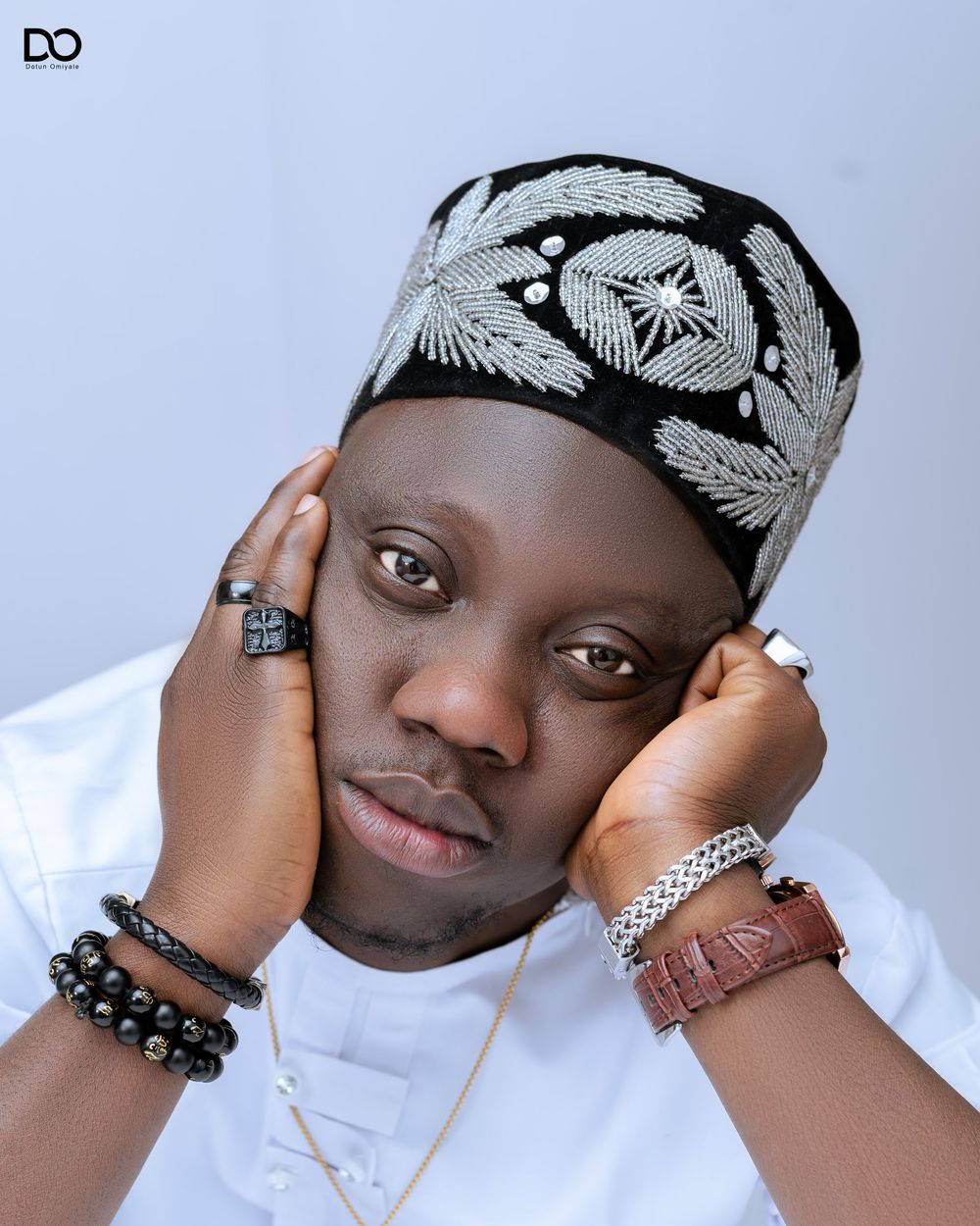 Portrait of person wearing white shirt and patterned headband with jewelry accessories.