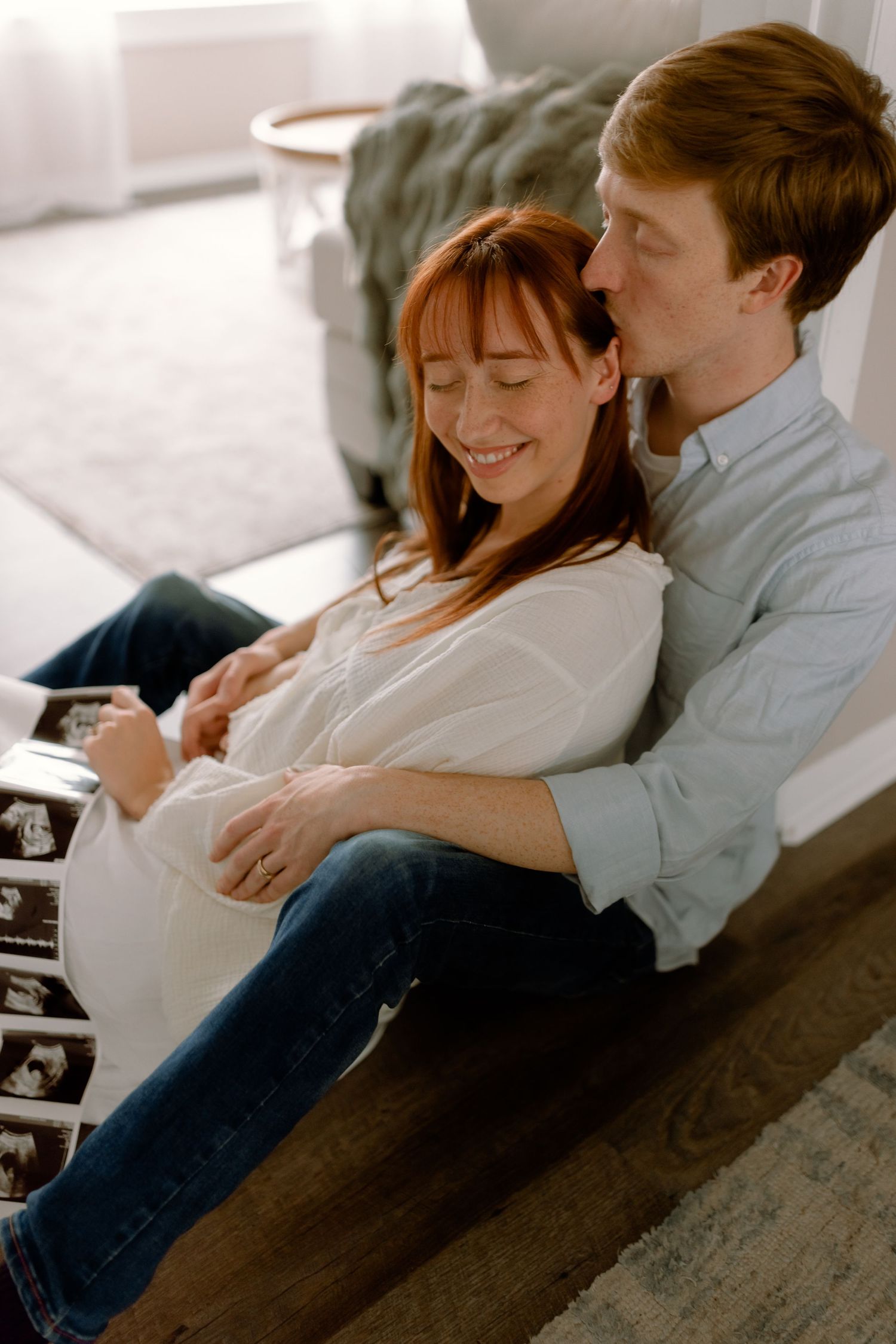 A loving family moment captured outside a brick house with a baby.