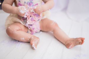 Close up of baby's legs and feet with pink decorative elements during cake smash session.
