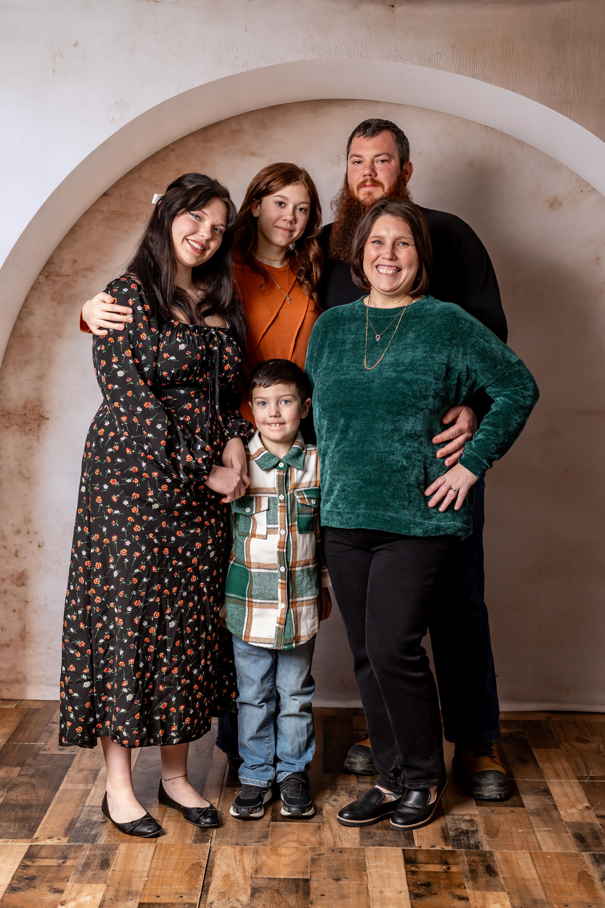 A family group of five posing for a formal portrait under an arched entryway.