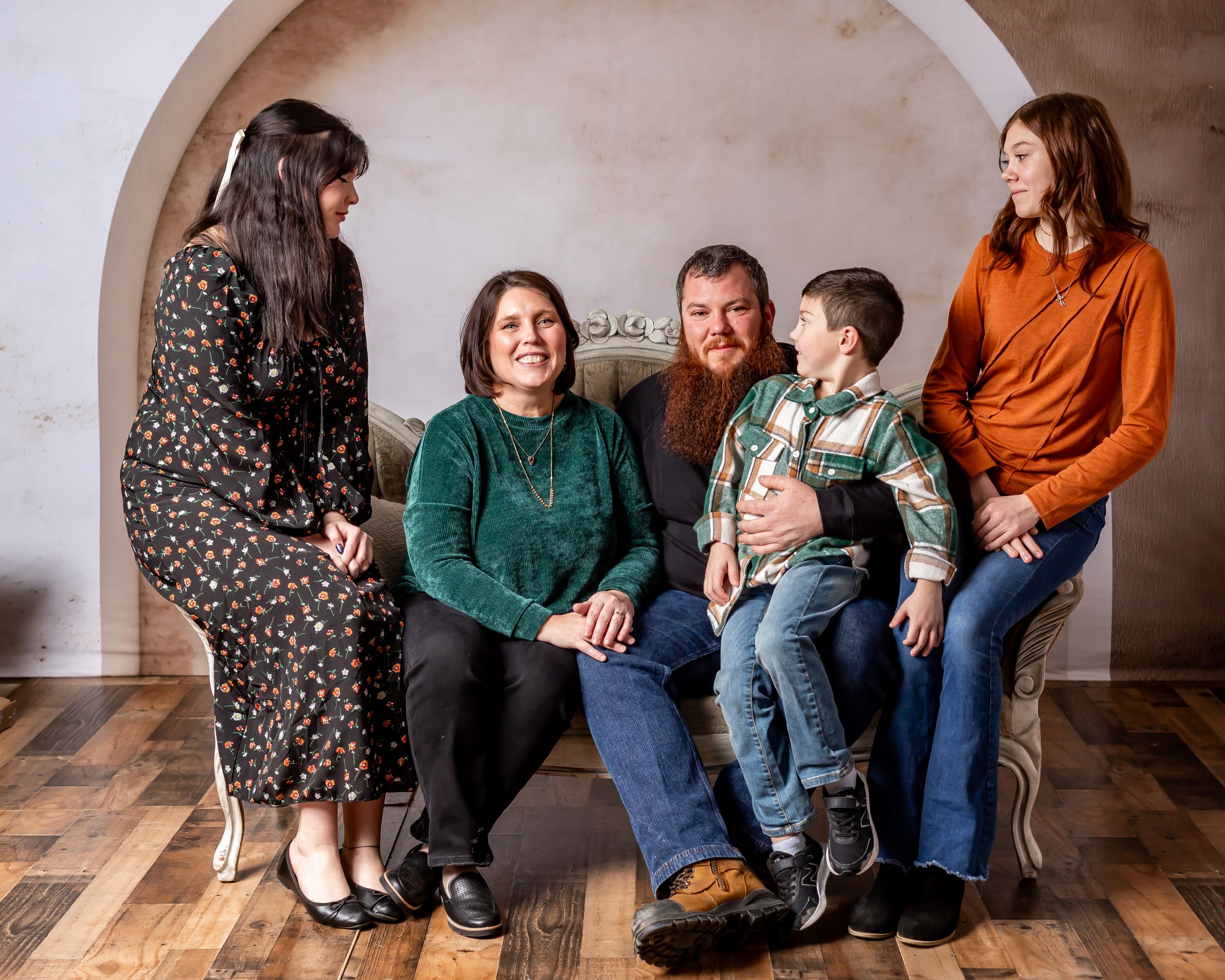 Casual family photo session with everyone arranged on and around a wooden bench.