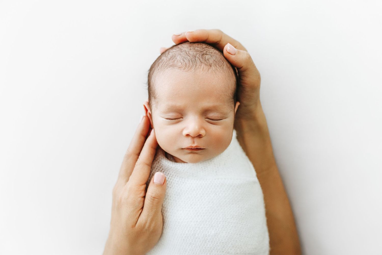 Newborn baby swaddled, lovingly caressed by Mom's hands