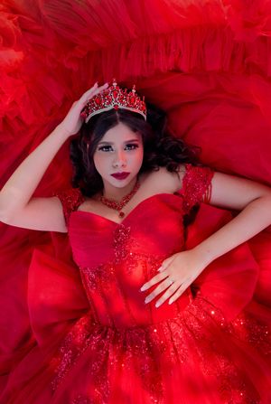 Young woman in red ballgown and jeweled crown poses elegantly for a quinceañera portrait. Toronto and GTA
