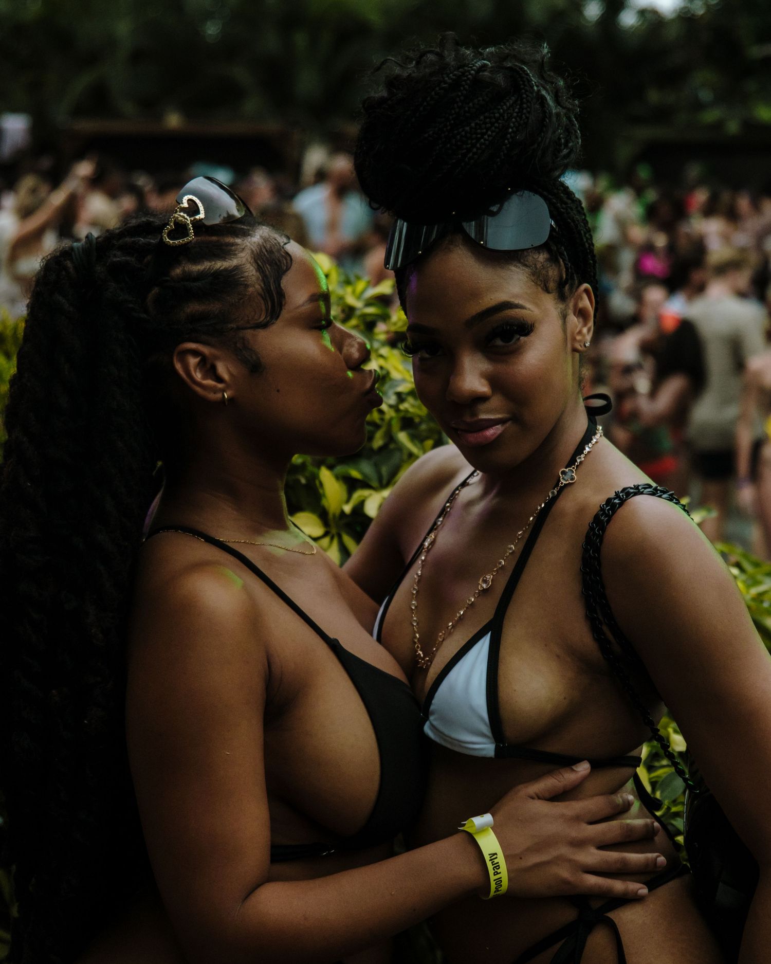 Two people sharing an intimate moment at an outdoor festival with a crowd visible in the background.