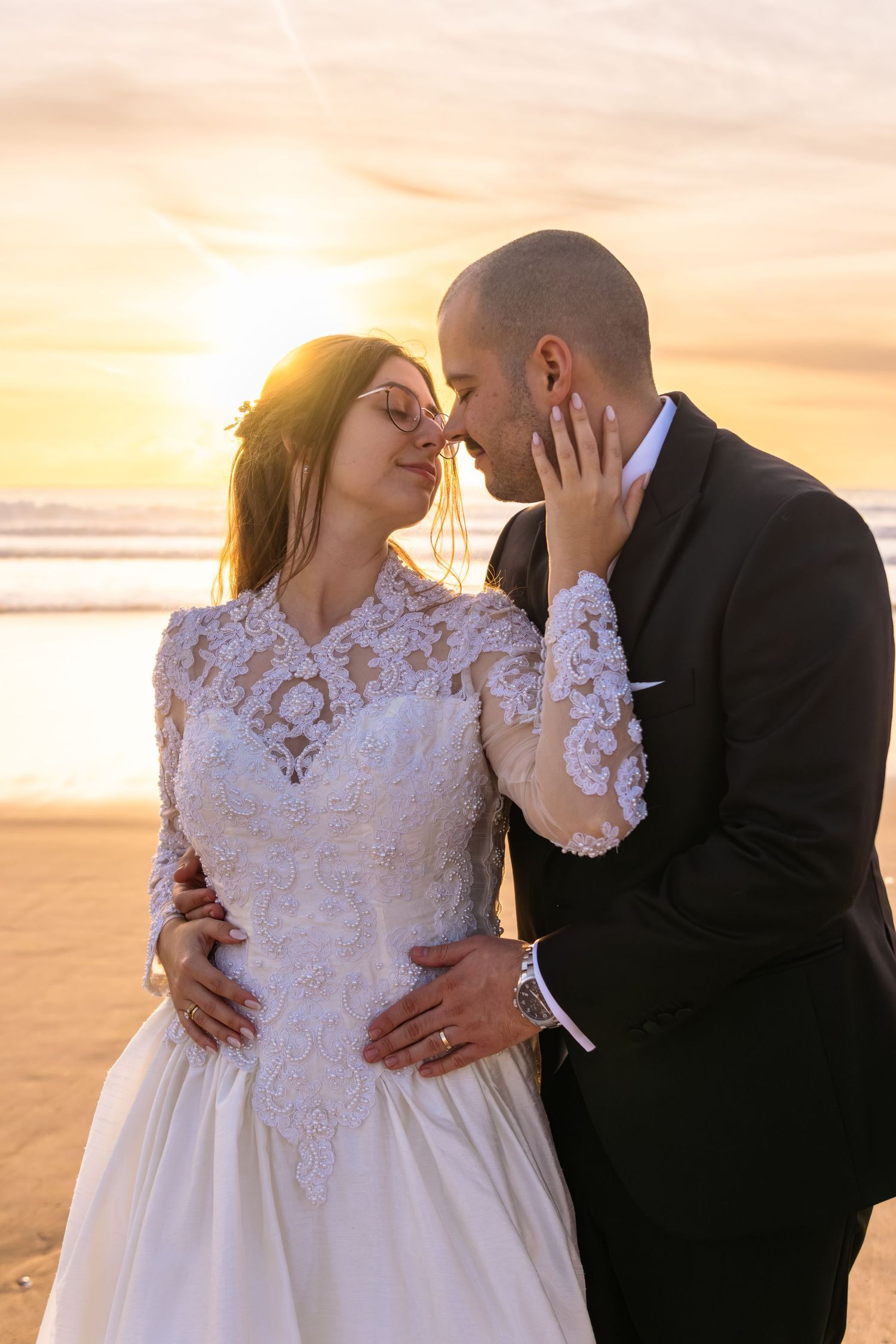 Romantic beach wedding portraits showing tender moments between newlyweds at sunset.