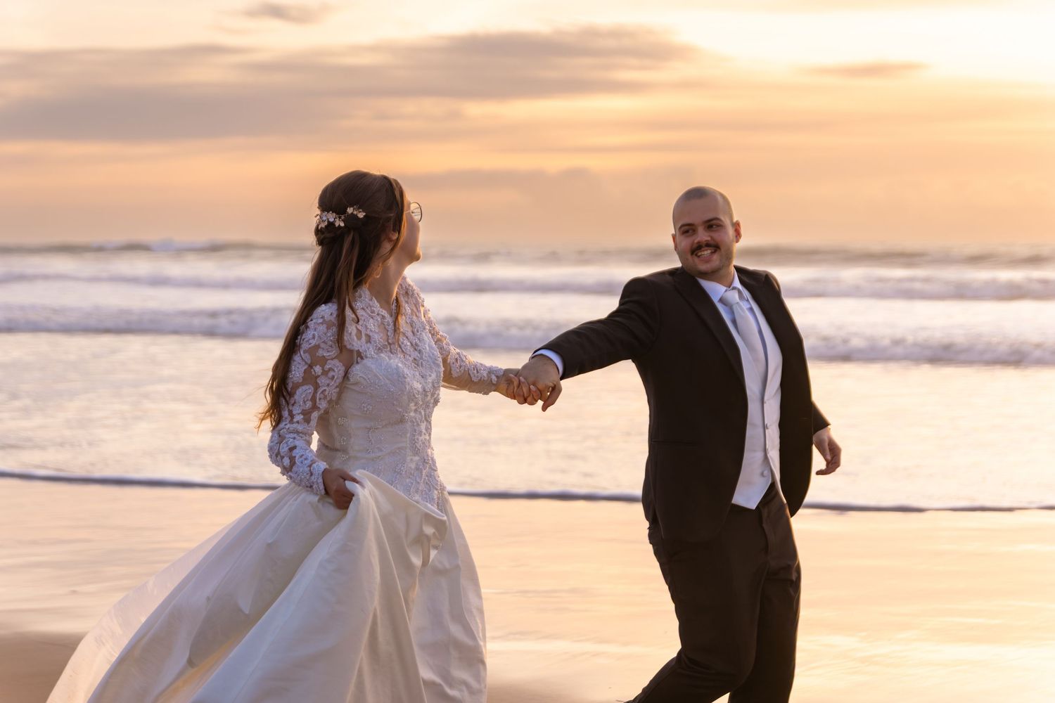 Bride and groom share a romantic moment while dancing on the shoreline.