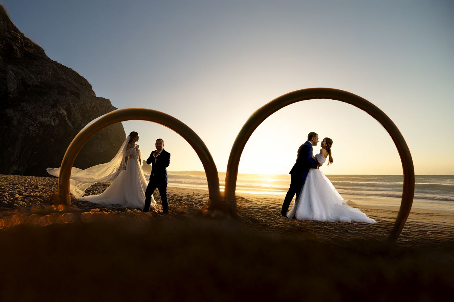 Silhouettes framed within wooden arches on beach during golden hour.