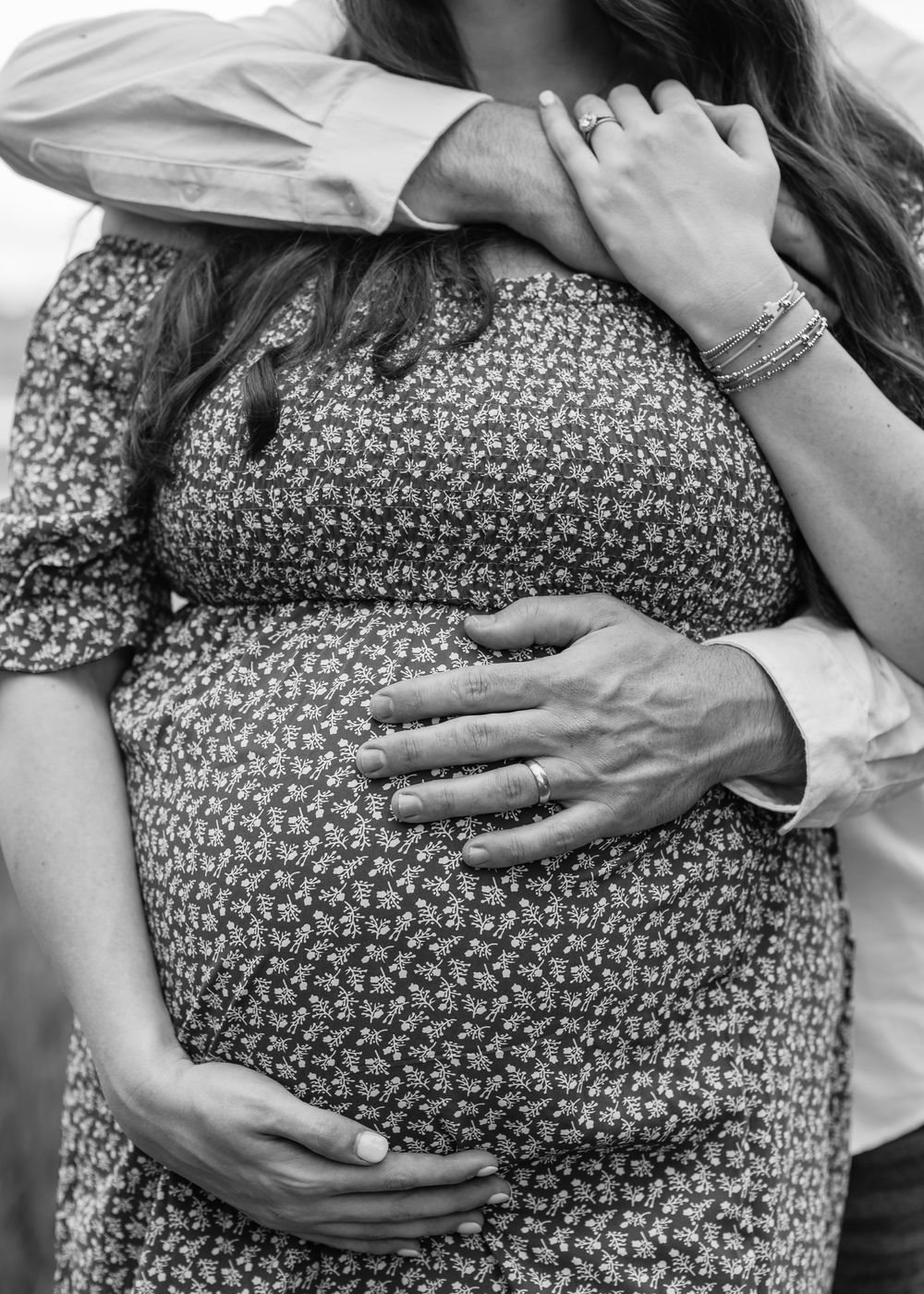 Black and white photo series showing a pregnant belly being cradled by caring hands in a floral dress.