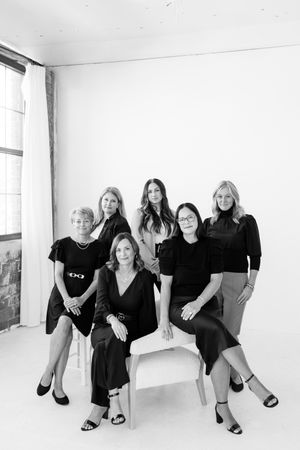 Professional group photo of team members in coordinated black and neutral outfits.