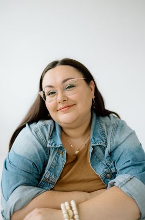 Portrait of person in denim jacket with natural lighting against white background.
