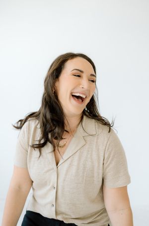 Candid laughing portrait against white background in casual attire.