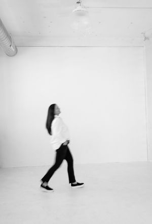 A minimalist black and white photo showing a silhouette walking across an empty white room.