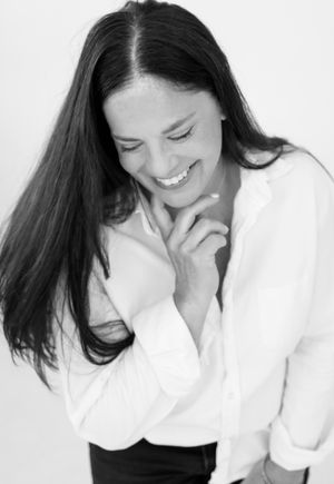 An intimate black and white portrait showing a gentle smile and downward gaze.