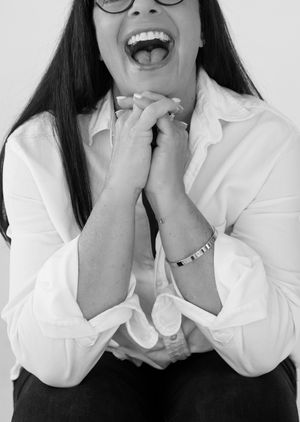 A playful black and white portrait of someone wearing glasses and showing excitement.