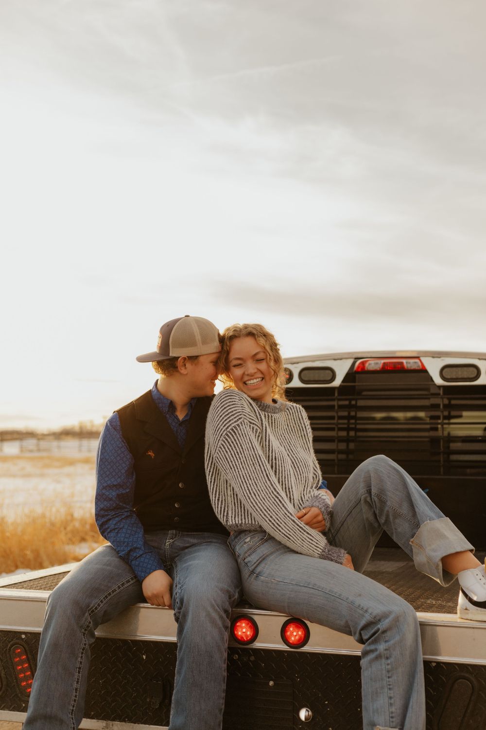 Western Couple sharing a romantic moment on pickup truck tailgate during sunset.