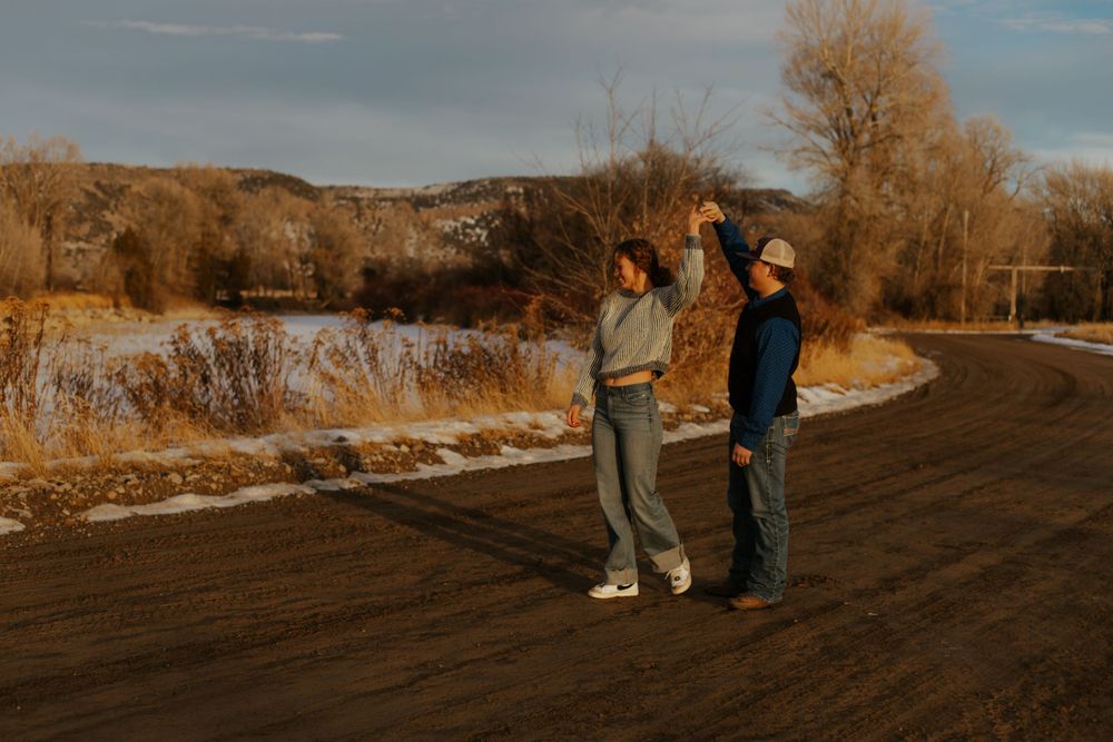 Western Couple dancing together along a scenic path during golden hour with autumn trees in the background.