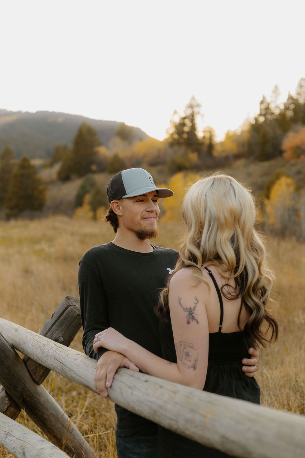 Couple sharing intimate moment while sitting on rustic log in mountainous autumn setting.