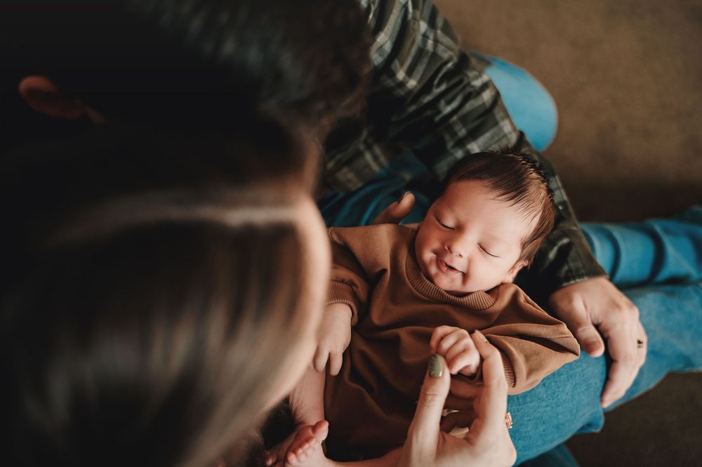 Close-up view of a sleeping infant wrapped in brown blanket on blue bedding.