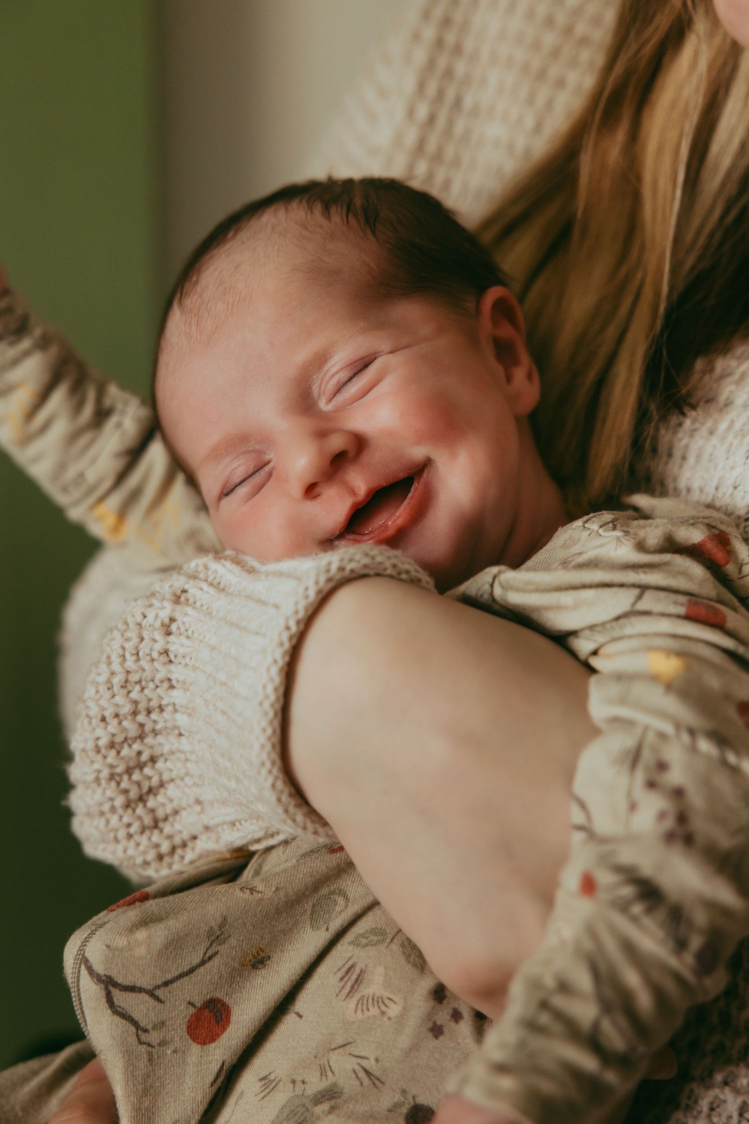 Peaceful newborn baby sleeps on soft white textured blanket in natural light.