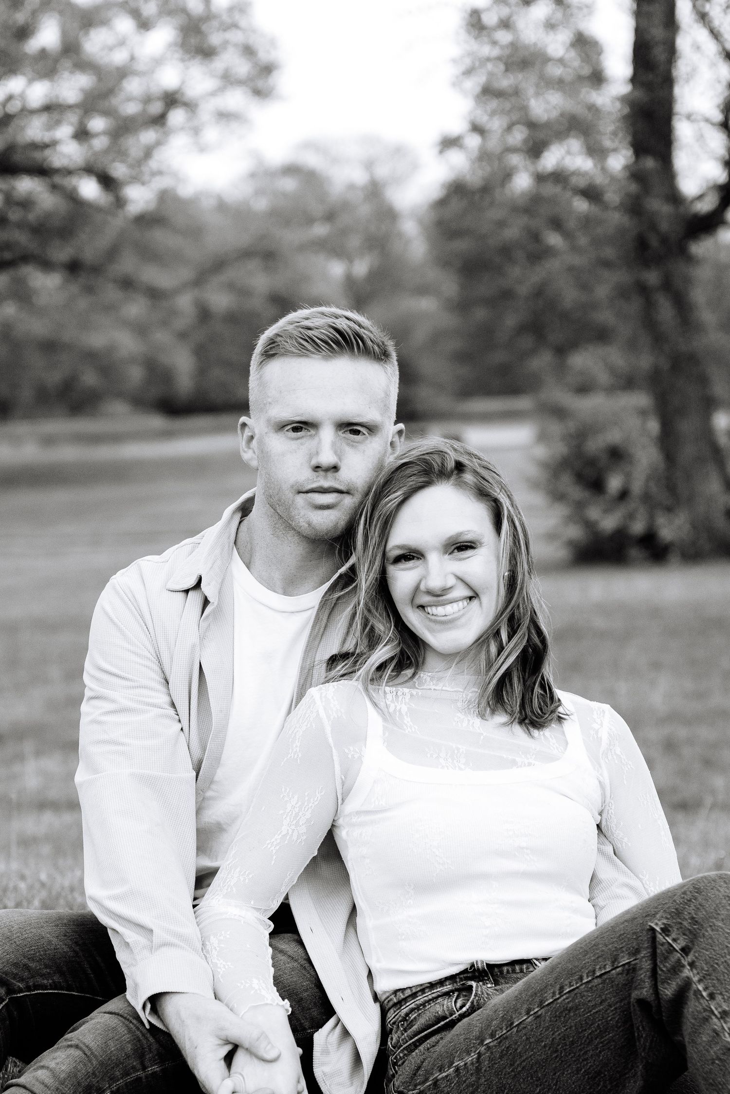 A black and white outdoor portrait of a smiling couple in casual attire.