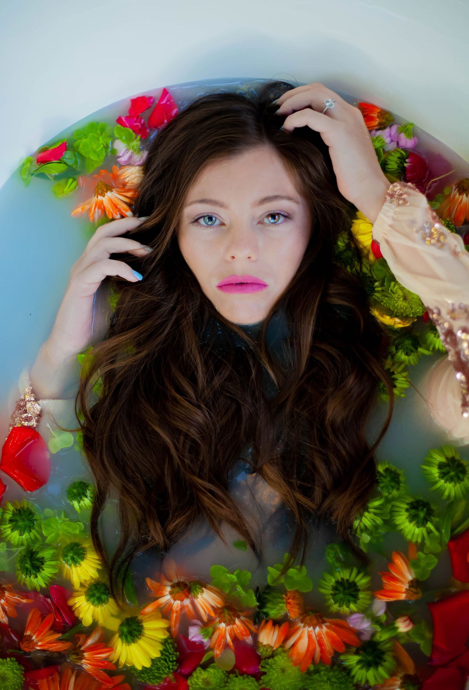 A woman poses in a bathtub with milk water and roses.