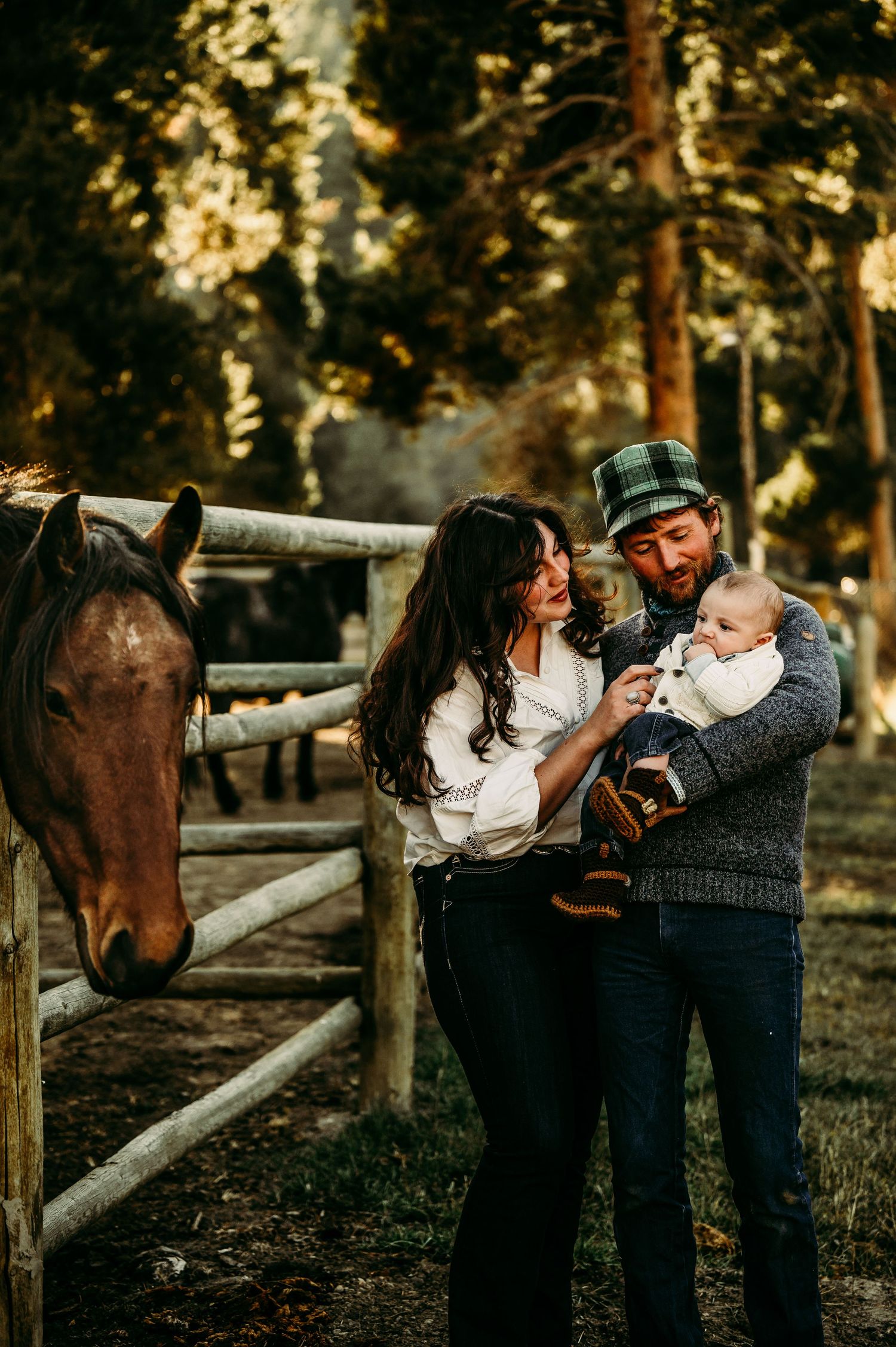 Family moment with horse at rustic wooden fence during golden hour.