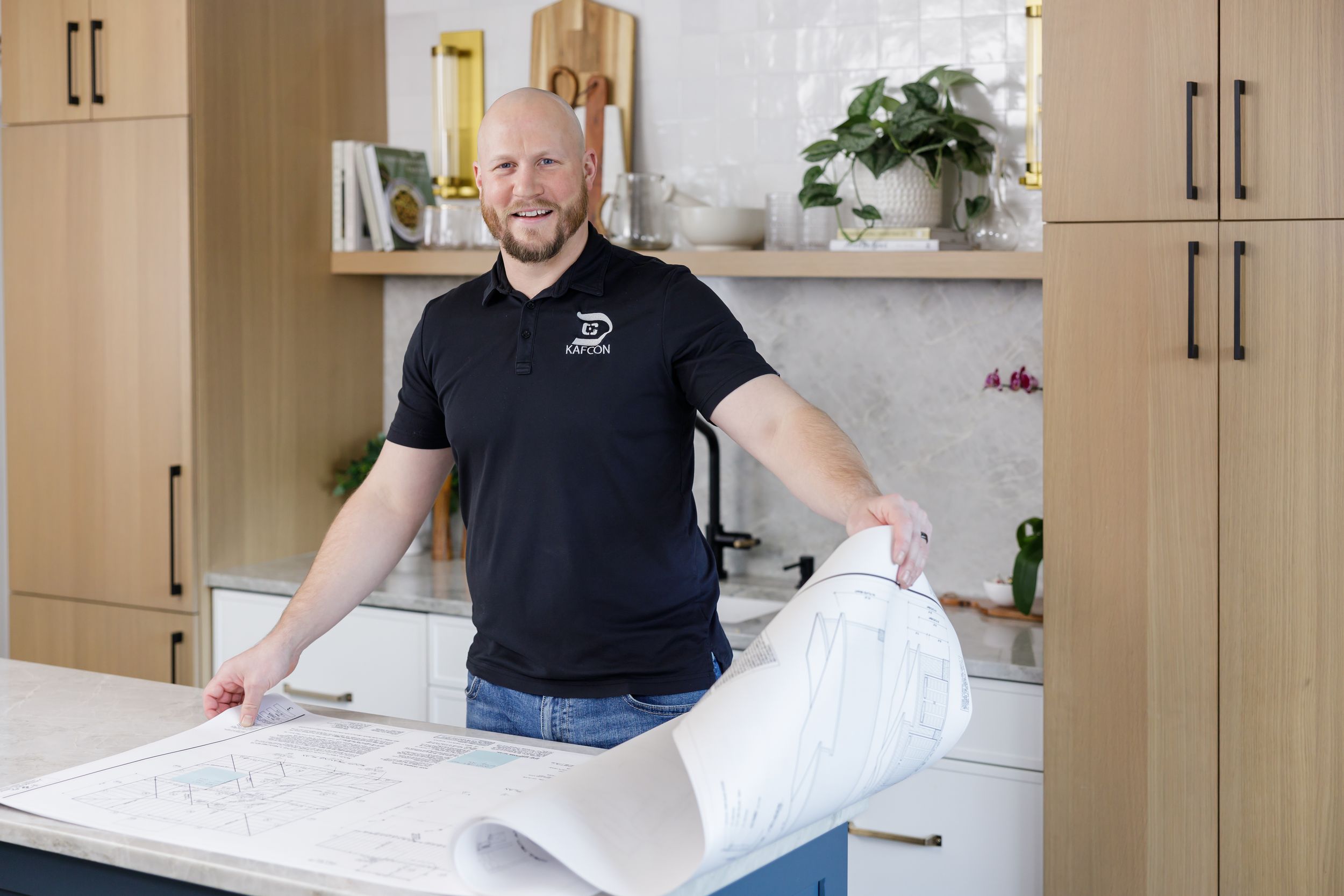 man construction business owner standing in kitchen flipping through blueprints for lifestyle branding photo in Maple Valley, WA