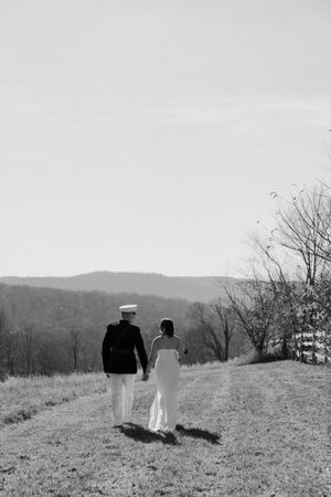 Black and white photo of bride and groom walking away from the camera. Mountains in the background.