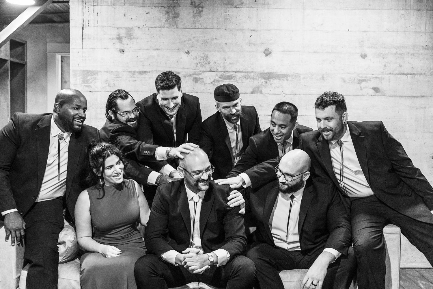 Black and white photo of groomsmen laughing and bonding before wedding ceremony.