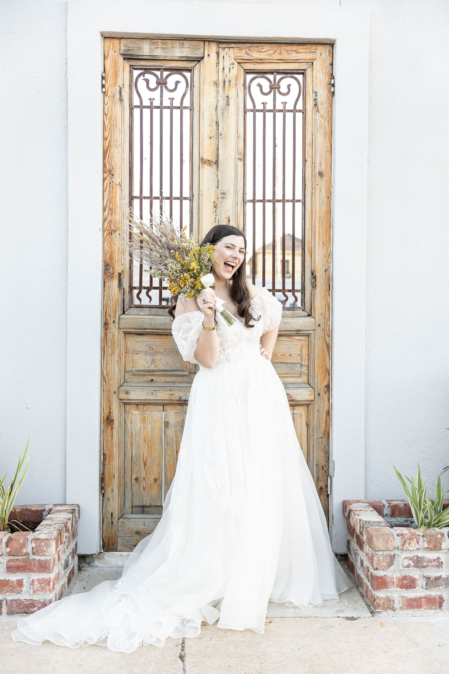 Bride in white gown poses in sequence against vintage wooden doors and white wall.