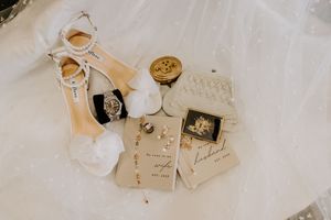 Elegant bridal accessories flat lay with heels, jewelry, and wedding stationery.