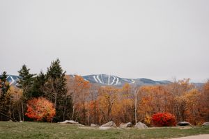 Scenic autumn landscape with colorful fall foliage and a ski mountain with trails visible in the background.