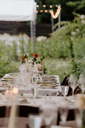 Elegant outdoor wedding reception table set with floral centerpieces, candles, and string lights.