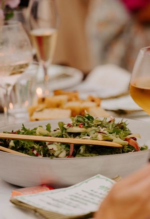 Fresh green salad with champagne and wine glasses on a wedding reception table.
