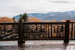 Scenic mountain view with ski slopes from rustic wooden deck railing in autumn.