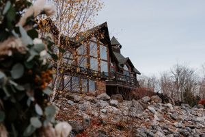Rustic A-frame wedding venue with large windows, string lights, and rocky landscape in autumn.