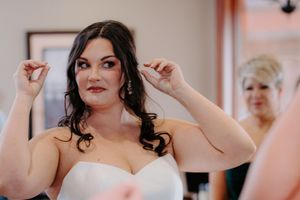 Bride putting on earrings while getting ready on her wedding day.