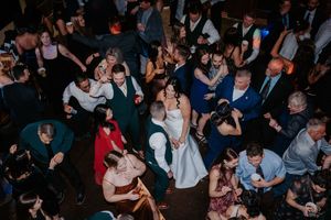 Aerial view of a lively wedding reception dance floor filled with guests surrounding the bride and groom.