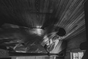 Black and white photo of a bride in a flowing wedding dress twirling in a wooden cabin room.