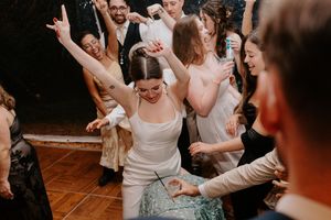 Bride in white dress dancing joyfully with wedding guests at lively reception party celebration.