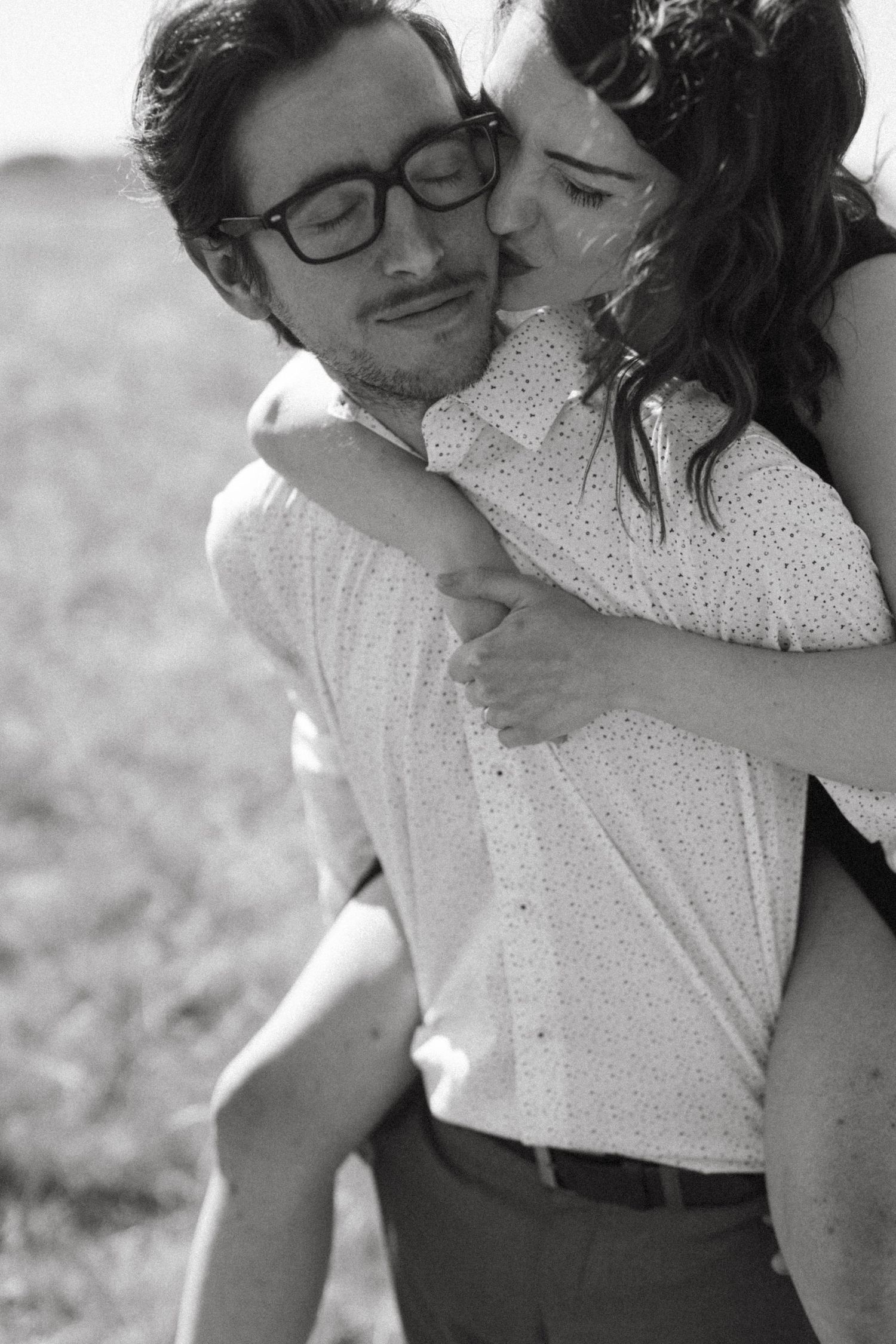 An intimate black and white portrait of a couple sharing a tender embrace.