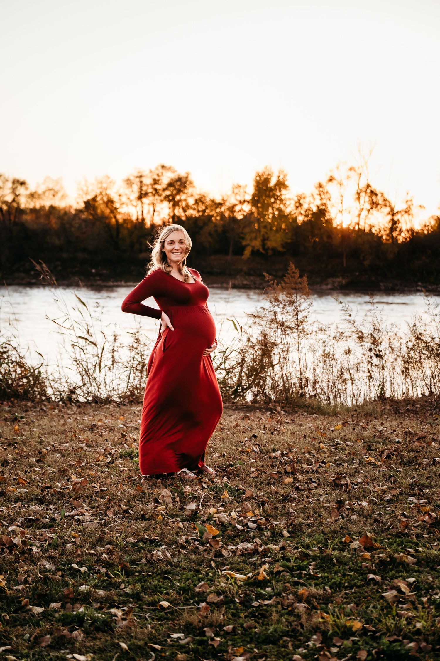 A pregnant woman stands by a body of water in a maternity session in Missouri.