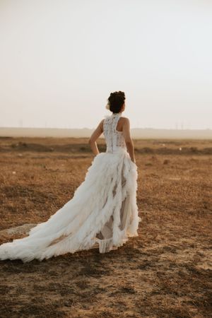 A dramatic wedding dress with flowing train photographed in golden hour light.