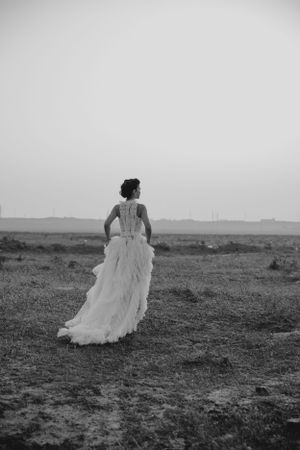 Black and white photo of a wedding dress with detailed back design in a desert setting.