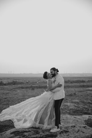 A black and white portrait of newlyweds sharing an intimate moment against a desert backdrop.