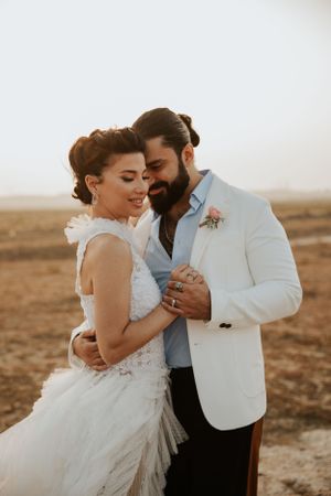 A couple shares a romantic moment in formal wedding attire during golden hour.